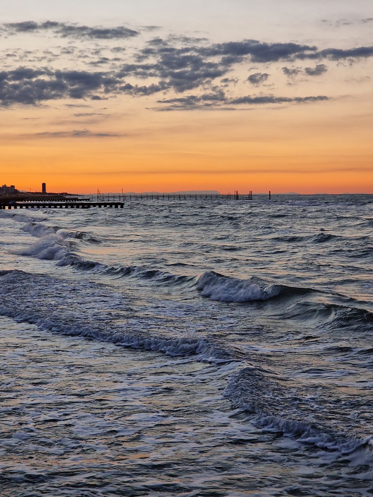 Zonsondergang boven de golven aan het strand van Lido di Jesolo